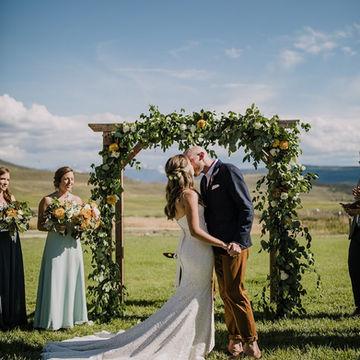 A bride and groom kissing at 4 Eagle Ranch's beautiful Sawatch Wedding Deck with mountain views in the background.