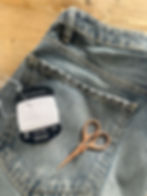 Denim jeans with sashiko thread, needle, and embroidery scissors