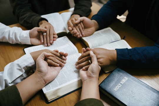 Group of Christians holding hands and praying during a Bible study