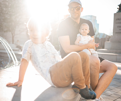 Two kids with dad at a beautiful fountain during golden hour captured by Toronto family photographer Laura MacB Photography