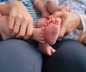 Close up of mom cuddling twin newborns feet during a Toronto newborn photography shoot with Laura MacB Photography