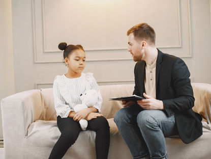 Enfant assise sur un canapé échangeant avec un adulte lors d’un entretien