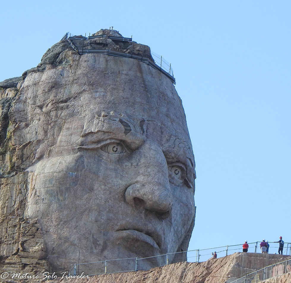 the mountain is carved into the face of Crazy Horse. People seen working near his face barely reach from his chin to his lower lip, the structure is that large.