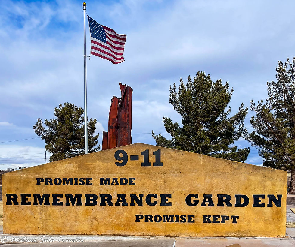 The American flag flies next to two beams from the destroyed New York City Twin Towns. the sign at the park says - 9-11 promise made remembrance garden promise kept