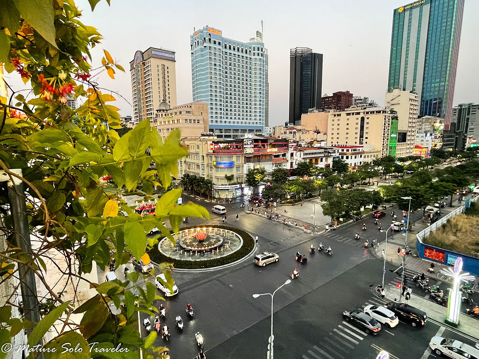 the rooftop view from the sixth floor of the Rex Hotel in District 1 Ho Chi Minh City Vietnam looks out over park and central fountain of district 1. In the distance are both modern glass high rise buildings and restored French Colonial skyscrapers.