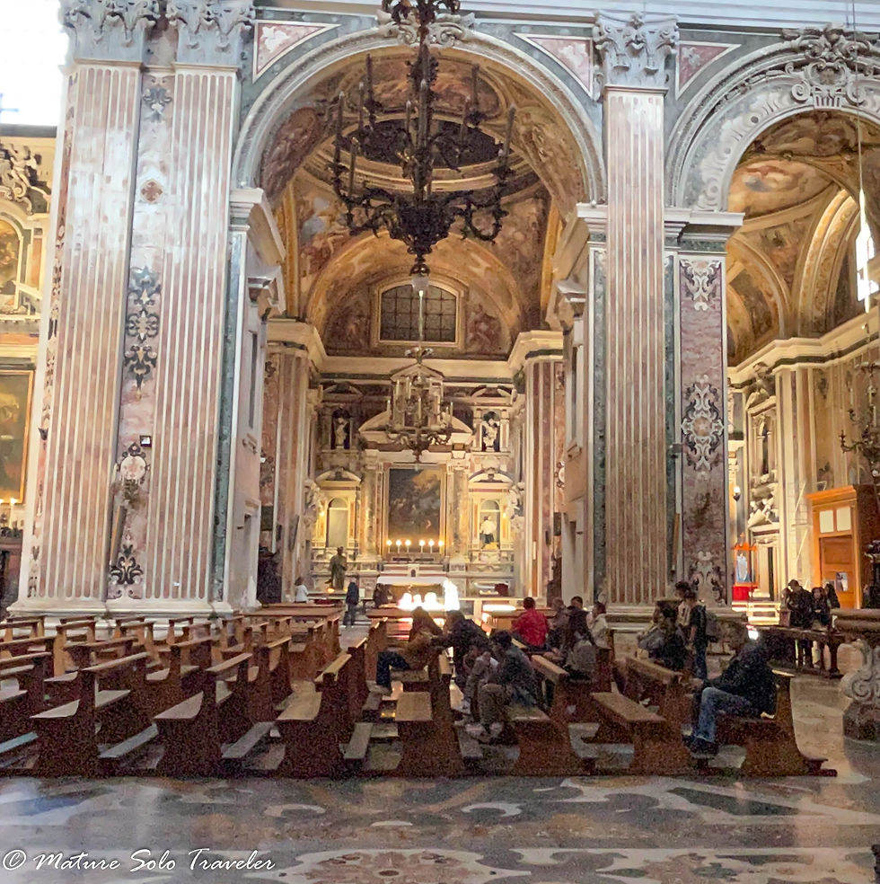 on church pews, worshippers wait their turn to see the statue of Saint Giuseppe Moscati. The tall marble columns are on the entry to the chapel where an altar and his tomb are situated..