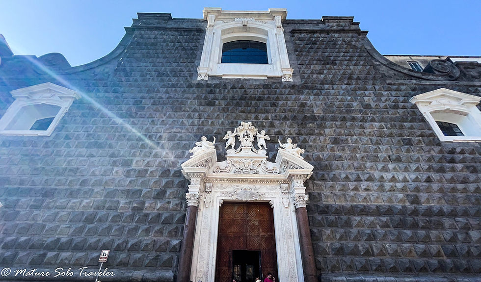 the outside facade of the church is covered in small square pyramid shaped blocks. Some ar eblack and some are grey. A door is situated central to the building with white marble carved surrounds. Two windows higher up on either side and one higher up above the door are also of white carved marble. It all looks very severe and imposing.