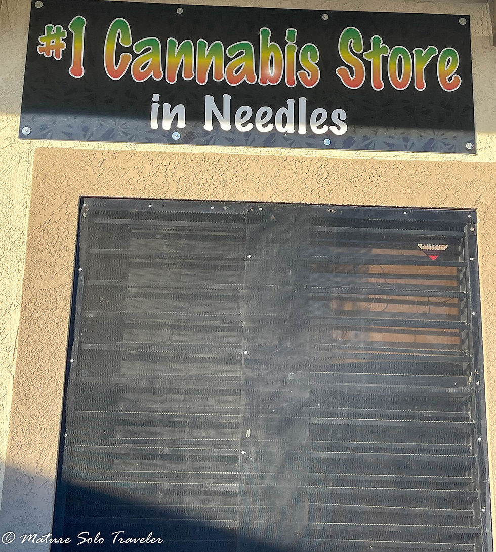 above a securely locked and bolted door is a sign. #1 Cannabis Store is painted in a top to bottom graduated colour scheme, green to yellow to red. under that in white it says "in needles". The sign has a black background