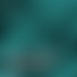 Três pessoas sorridentes trabalham juntas em frente a computadores, colaborando em um ambiente de escritório.