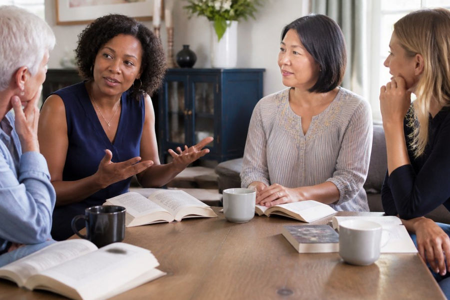 Diverse book club members discussing plot twists in popular medical mystery books around a wooden table