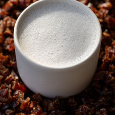 Plantaardige melk in een kopje met stukjes dadels eromheen