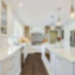 White kitchen with patterned backsplash, island, and dark wood floors