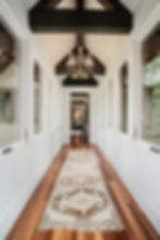 Long hallway with chandelier, hardwood floors, patterned rug