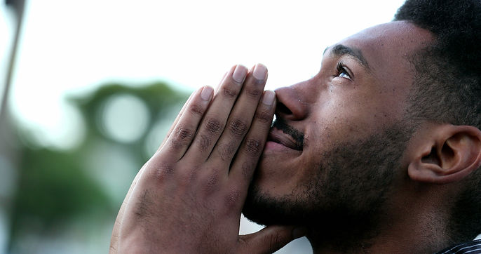 Spiritual young black African man praying to GOD. Person looking to sky with HOPE and FAIT