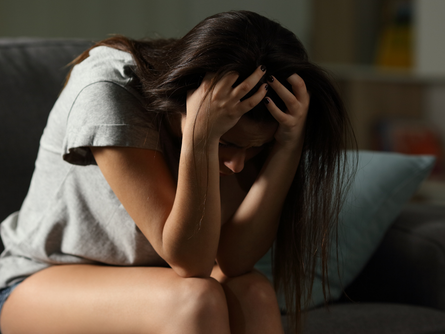 Person sitting with a drink, looking anxious, representing the link between alcohol and anxiety.