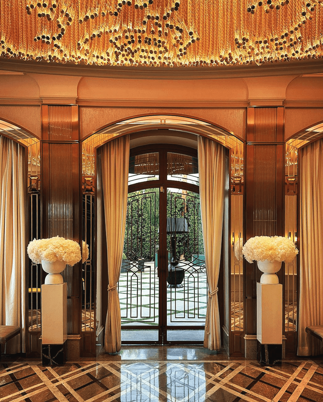 Elegant hotel entrance with glass door and decorative floral arrangements