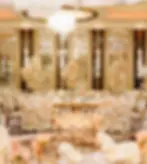 Elegant ballroom decorated with flowers, tables, and a chandelier for a wedding.