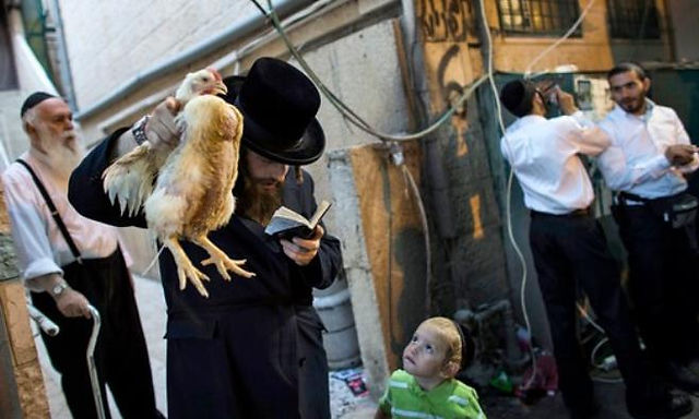 An Orthodox Jewish man participating in the ceremony called "Kaparot", involves waving a live chicken above one's head