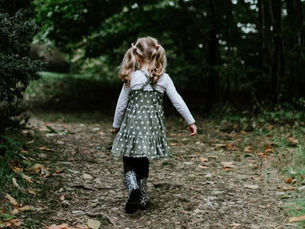 Ein blondes Mädchen läuft auf Waldweg.