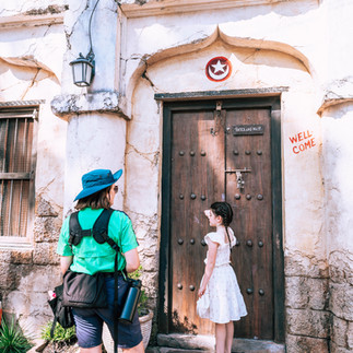 Disney Castmember taking a photo of a young girl knocking on a door at Animal Kingdom