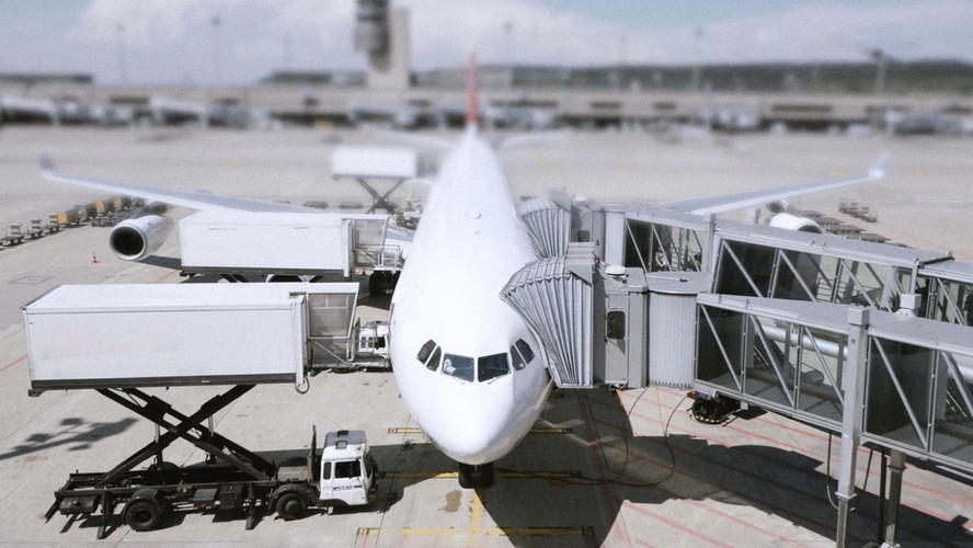 An aeroplane docked at an airport gate, surrounded by loading equipment and connected to a jet bridge. Text overlay reads: “Modern air cargo is embracing smart technologies.