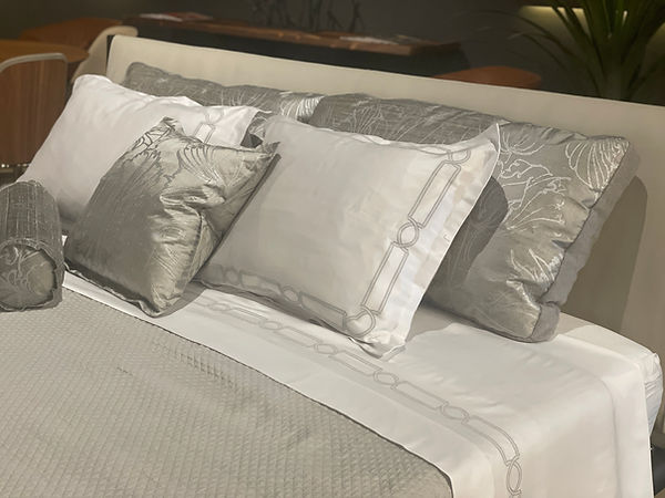 Kearsley luxury Italian linens in extra-long staple Egyptian cotton sateen with molding embroidery, taupe Egyptian cotton matelassé coverlet, and Barbara Beckmann batik silk tulip hand-painted pillows. King pillows feature St. Anton Mongolian cashmere backs; neck roll and throw pillows available.
