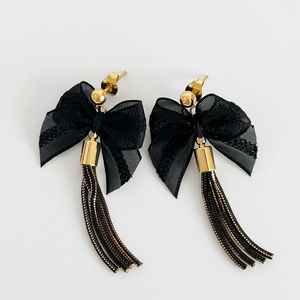 Boucles d'oreilles pendantes pompon noir et or avec nœuds en voilette, vues à plat sur fond blanc.