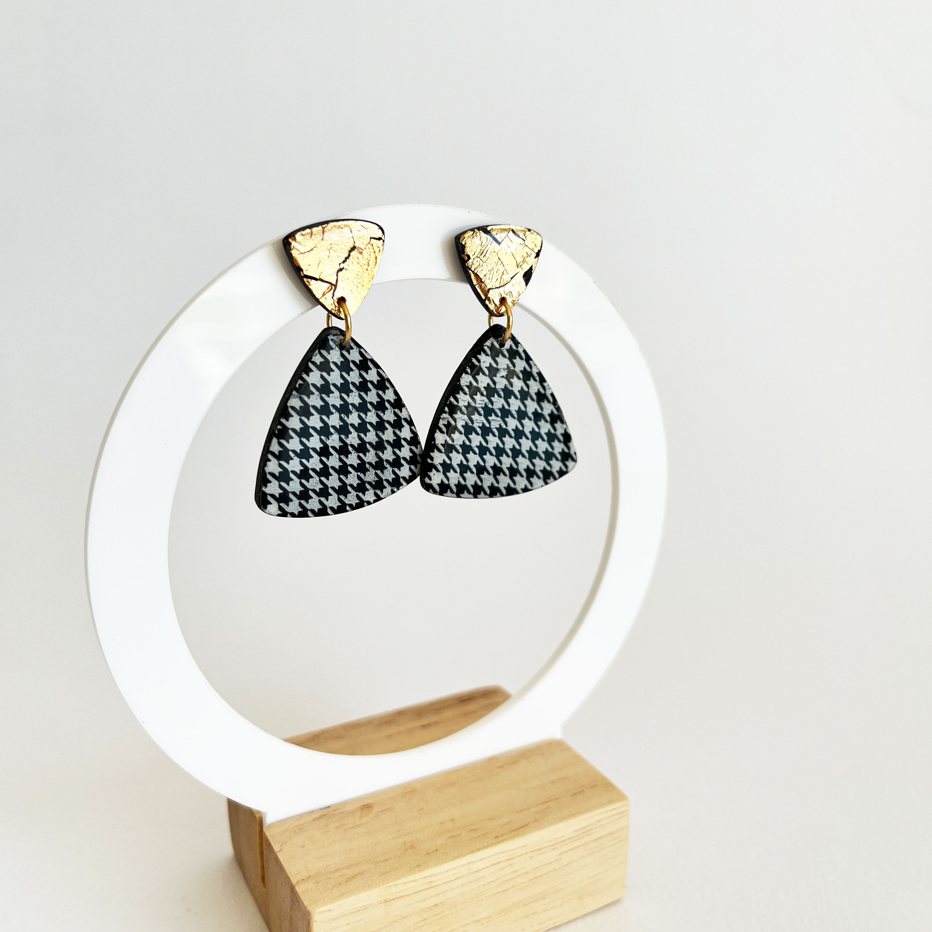 Boucles d'oreilles St Germain Triangle sur présentoir blanc rond et socle en bois.
