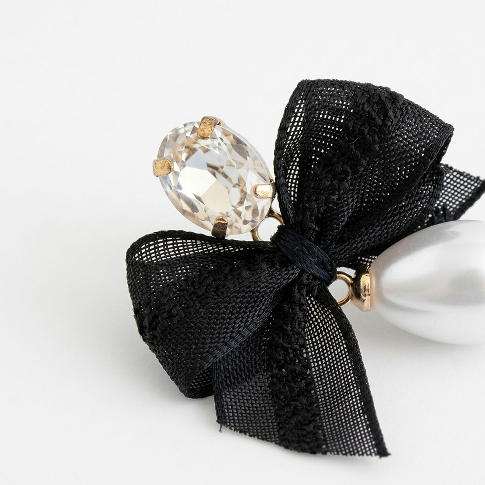 Gros plan sur boucle d'oreille : nœud en voilette noire, grand cristal ovale serti de doré, perle goutte