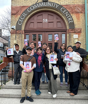 Terri stands in the middle of a group of volunteers on the doorsteps of the Cecil Community Centre. Her volunteers are holding clipboards showing her campaign materials. They have an image of Terri in an orange shirt on a purple background.