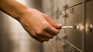 A person putting a key into a safe deposit box