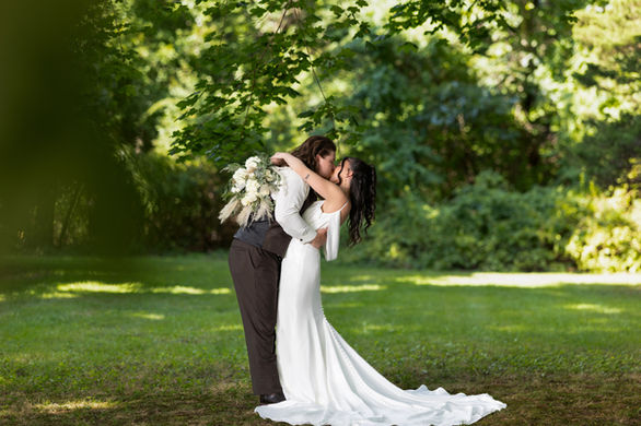 Bride and groom kissing and posing for a romantic portrait during a backyard wedding ceremony.