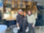 zwei Männer und eine Frau vor einem schwarzen Foodtruck