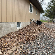 the side of a house with leaves in the landscaping