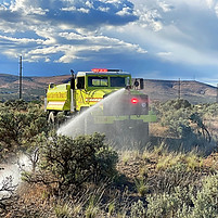 Firetruck spraying water on brush fire
