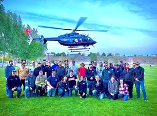 Firefighters posing in front of helicopter hovering above them