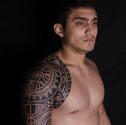 Polynesian blackwork tattoo covering the shoulder and upper arm and extending onto the chest, with intricate geometric and curved patterns.