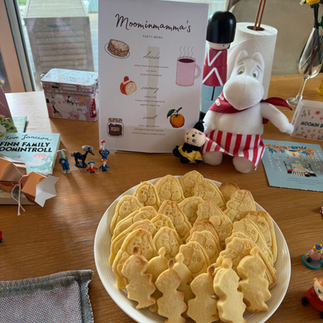 This image shows a Moominmamma plushie and a plate full of Moomin biscuits.