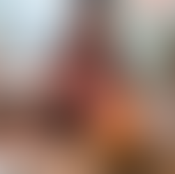 Image of Saffron, a young woman wearing a pink shirt, smiling and sitting behind a birthday cake with the candles lit.