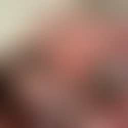 Saffron lies in her pink bed under the covers with her teddy bear.