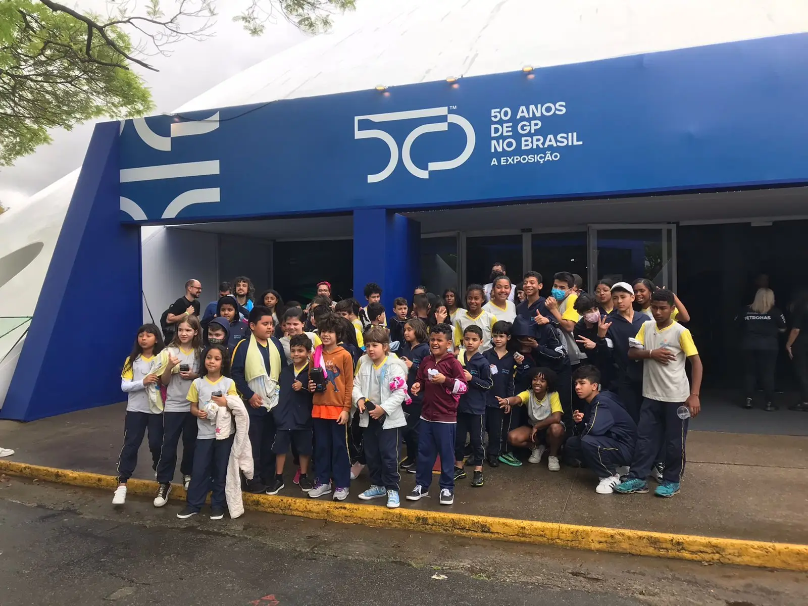 Grupo de estudantes em frente à entrada azul da exposição, na Oca