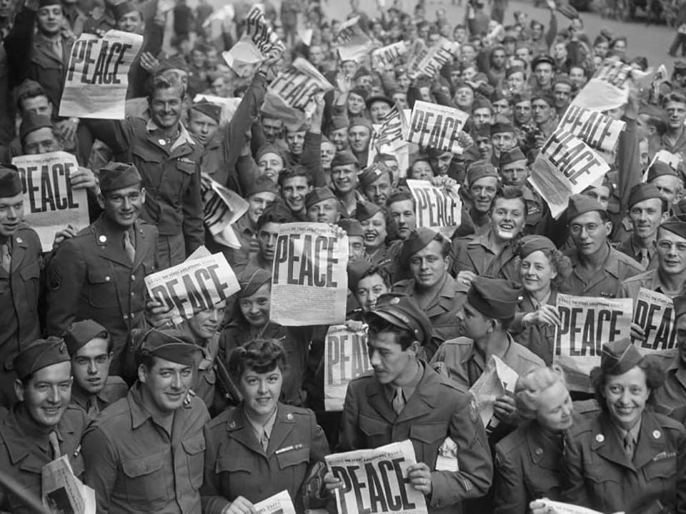Soldiers holding newspapers with the word PEACE written in big bold letters.