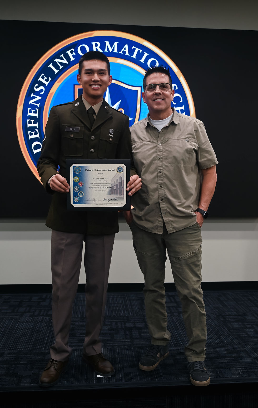 Cameron Villa (trái) và cha Rene Villa tại Trường Thông tin Quốc phòng ở Fort Meade, Maryland, ngày 10/4/2025. Cameron được công nhận là Sinh viên Tốt nghiệp Danh dự Xuất sắc trong lễ tốt nghiệp Khóa học Nền tảng Truyền thông Đại chúng.
