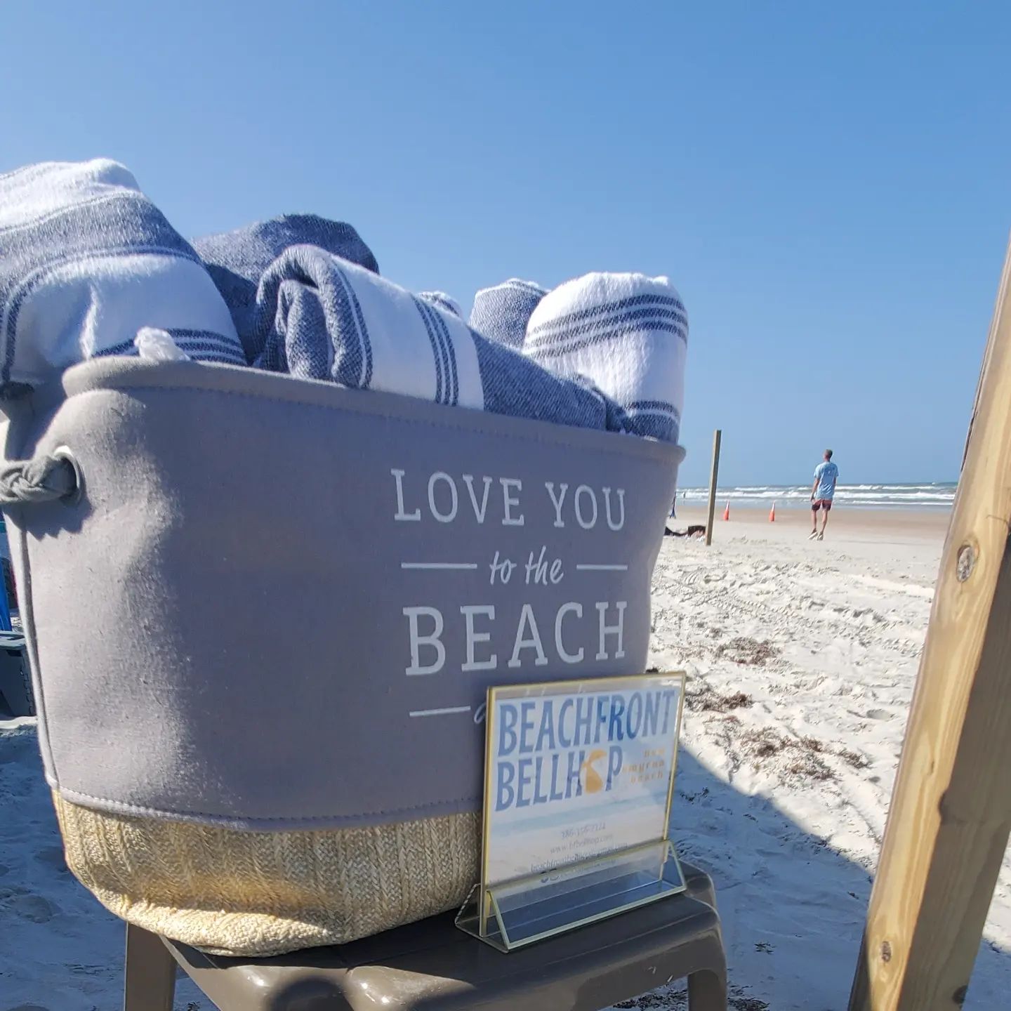 Rolled towels sit in a basket with New Smyrna Beach in the background