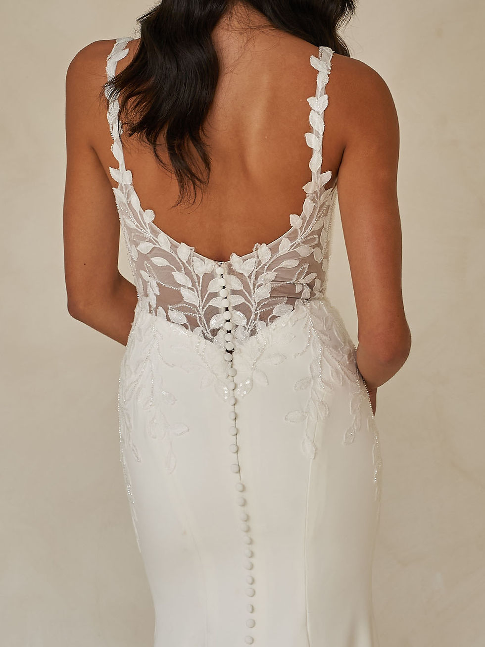 Thumbnail: Back view of Wray Bodice by Madi Lane wedding dress with sheer lace back, covered buttons, and fitted crepe skirt.