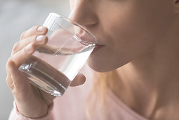 Close up cropped image thirsty woman holding glass drinks still water preventing dehydrati