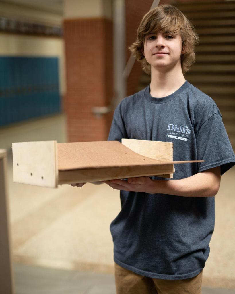Oskar pictured wearing a grey shirt holding a wooden ramp