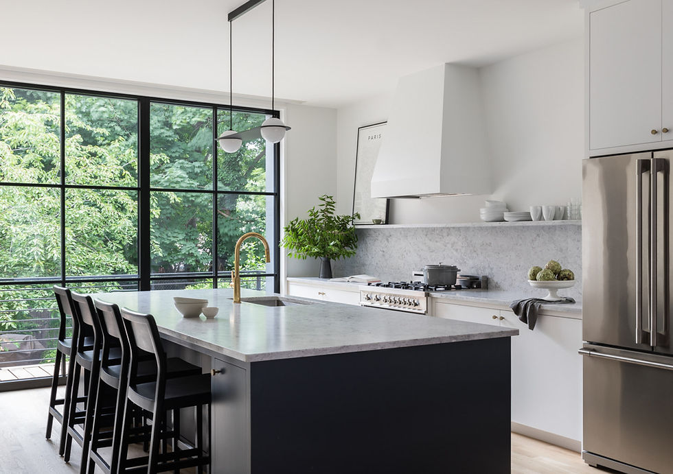 The architects chose Carrara marble for the kitchen countertops and backsplash and painted the kitchen island cabinets Farrow & Ball Railings. A Laurent 03 fixture from Lambert & Fils hangs over the island, the minimalist cabinet hardware is from Omnia, the faucet is from California Faucets, and the refrigerator is Electrolux.