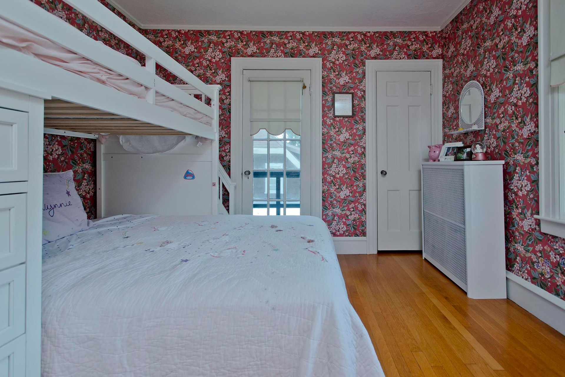 A floral wall papered bedroom with white doors. There's several closets and it comfortably fits a queen bed. 