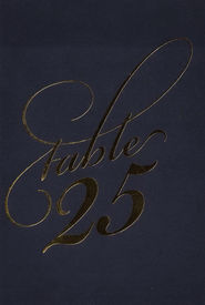 A paper table number label for a wedding; black paper with a gold cursive font.